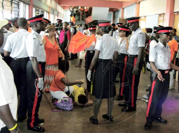 Photo by Daraine Luton
Police surround a woman who fainted in a corridor outside the main hall of the National Arena.