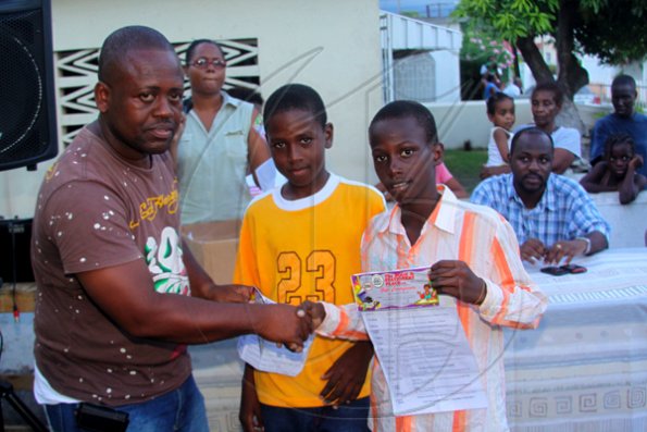 Anthony Minott/Freelance Photographer
Keith Blake (left), Councillor for the Independence City Division hands over book vouchers to Jamar Samuels (right), and Ronaldo Able during a back-to-school project instigated by Councillor for the Independence City Division, Keith Blake.