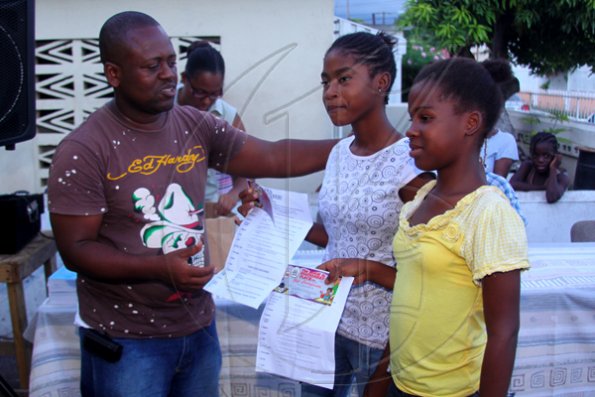 Anthony Minott/Freelance Photographer
Keith Blake (left), councillor for the Independence City Division hands over book vouchers to two students from his division during a back-to-school project instigated by Councillor Blake recently.
