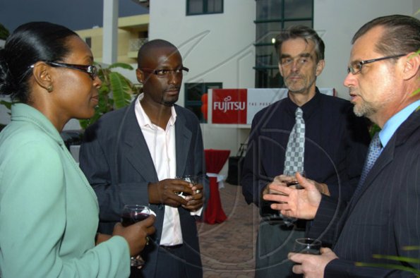 Peta-Gaye Clachar/Staff Photographer
President and CEO of Fijitsu Caribbean Mervyn Eyre (right) is engaged in conversations with Diann Campbell (left) from the Ministry of Education, Clive Allen (second left) the Executive Vice President of Fijitsu Managed Services and Mark Hopkins Executive Vice President of Fijitsu Project Management in the Caribbean at the Fijitsu executive cocktail reception at their Belmont Road office on Thursday, March 12, 2009.
