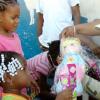 Norman Grindley /Chief Photographer
Executive Director of the National Solid Waste Management Authority (NSWMA), Joan Gordon-Webley, hands a toy to one year-old Kevette Kirby, who gracefully accepts. The infant and other children who were presented with gifts, were left homeless after fire destroyed their homes on West Street in Kingston last Thursday. Gordon-Webley visited them yesterday. 

. O one of the eighteen families who was left homeless after gutted several homes on West Street in Kingston last Thursday morning, seems very surprise as she received a doll from Gordon-Webley at her burnt home.