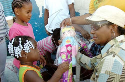 Norman Grindley /Chief Photographer
Executive Director of the National Solid Waste Management Authority (NSWMA), Joan Gordon-Webley, hands a toy to one year-old Kevette Kirby, who gracefully accepts. The infant and other children who were presented with gifts, were left homeless after fire destroyed their homes on West Street in Kingston last Thursday. Gordon-Webley visited them yesterday. 

. O one of the eighteen families who was left homeless after gutted several homes on West Street in Kingston last Thursday morning, seems very surprise as she received a doll from Gordon-Webley at her burnt home.