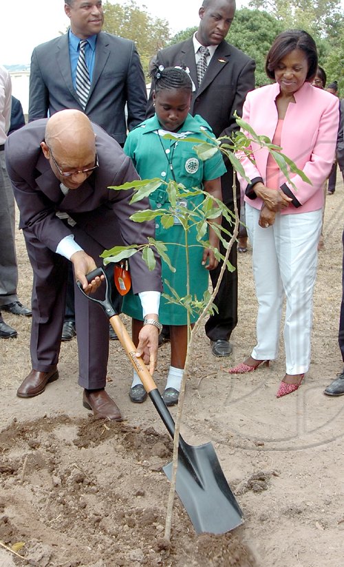 Rudolph Brown/Chief Photographer
Governor General Dr Patrick Allen (left) plants a tree during the launch of the National Tree Growing programme at King's House yesterday while his wife Patricia Allen and Aurian Harris, student of St Martin's Primary School, look on. Also pictured are members of the governor general's security detail.