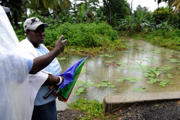Ricardo Makyn/Staff Photographer.
Residents of Hope Bay look at the Gully that a  Ill Fated bus  ran into  in Hope Bay Portland killing two and also a Five yearold Child is missing.
