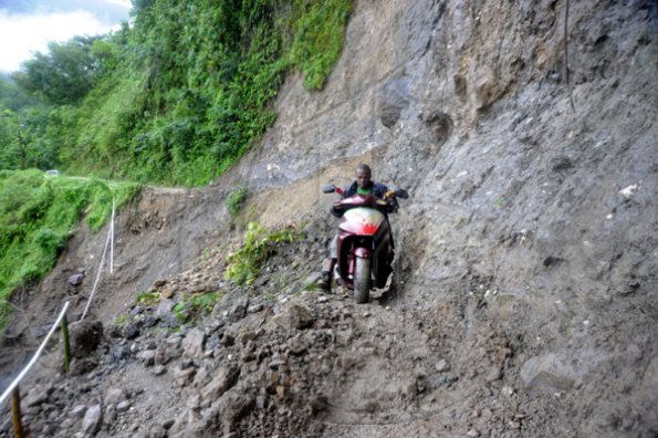 Ricardo Makyn/Staff Photographer.
John Beckford dangerously rides His bike along whats left of a embankment at Friday in the  Rio Grande Valley after Rainfall had caused a Landslide that totally destroyed what was left of the roadway .